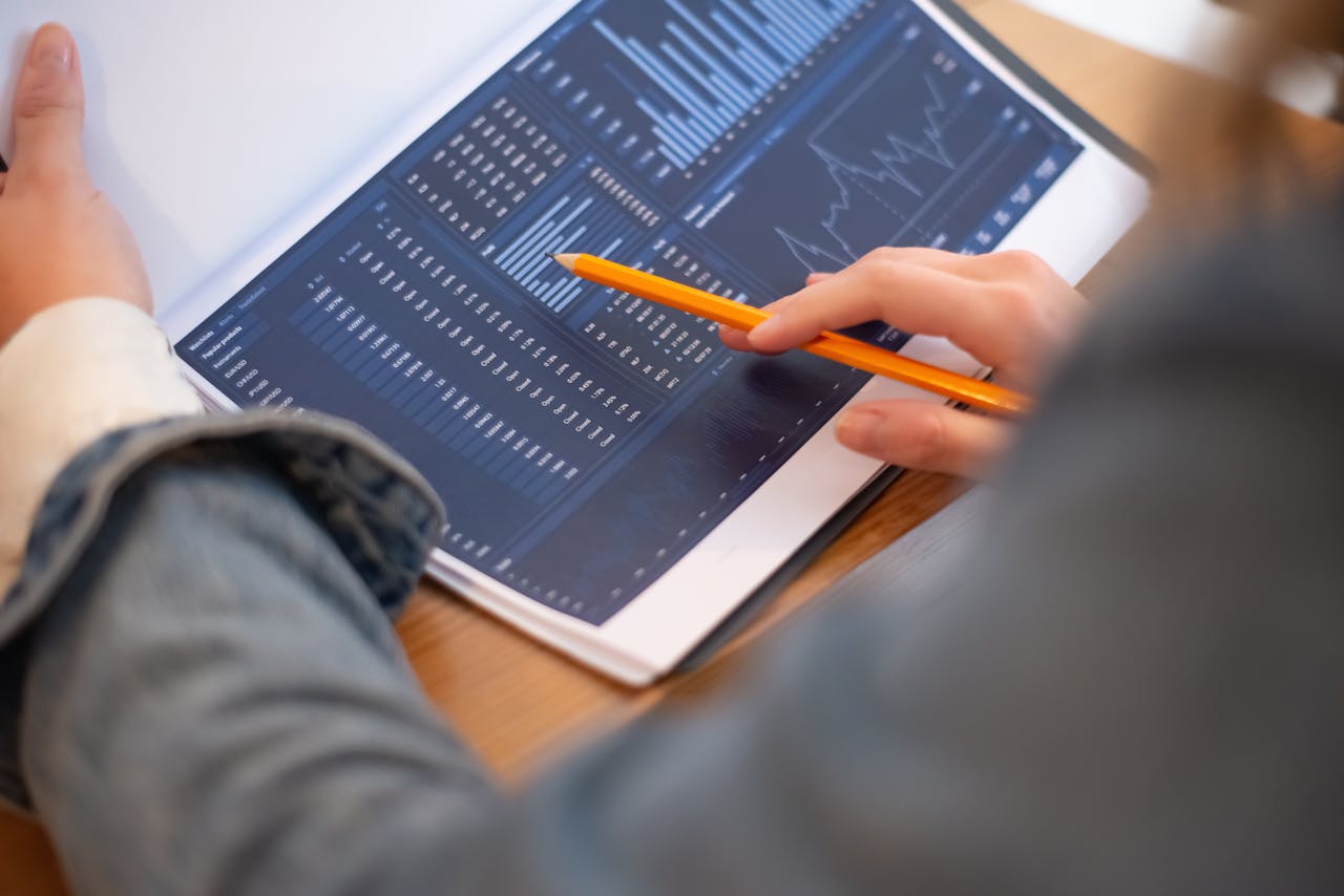 Focused image of hands analyzing business graphs and charts in a folder, highlighting data insights.