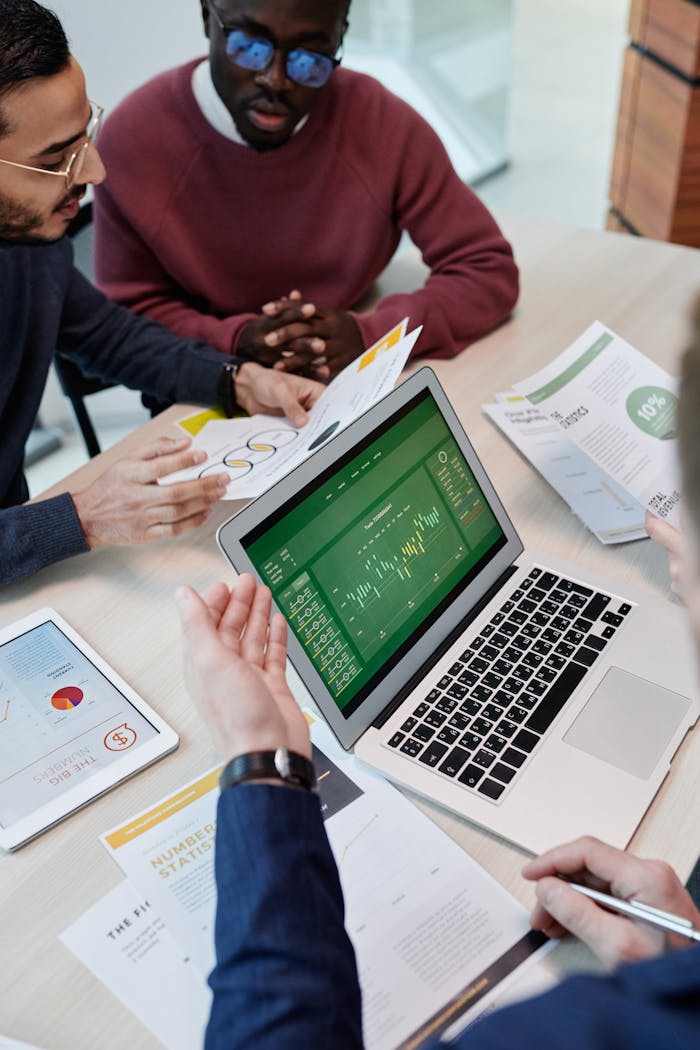 A multicultural team engaged in a collaborative meeting with a laptop and documents in a modern office setting.